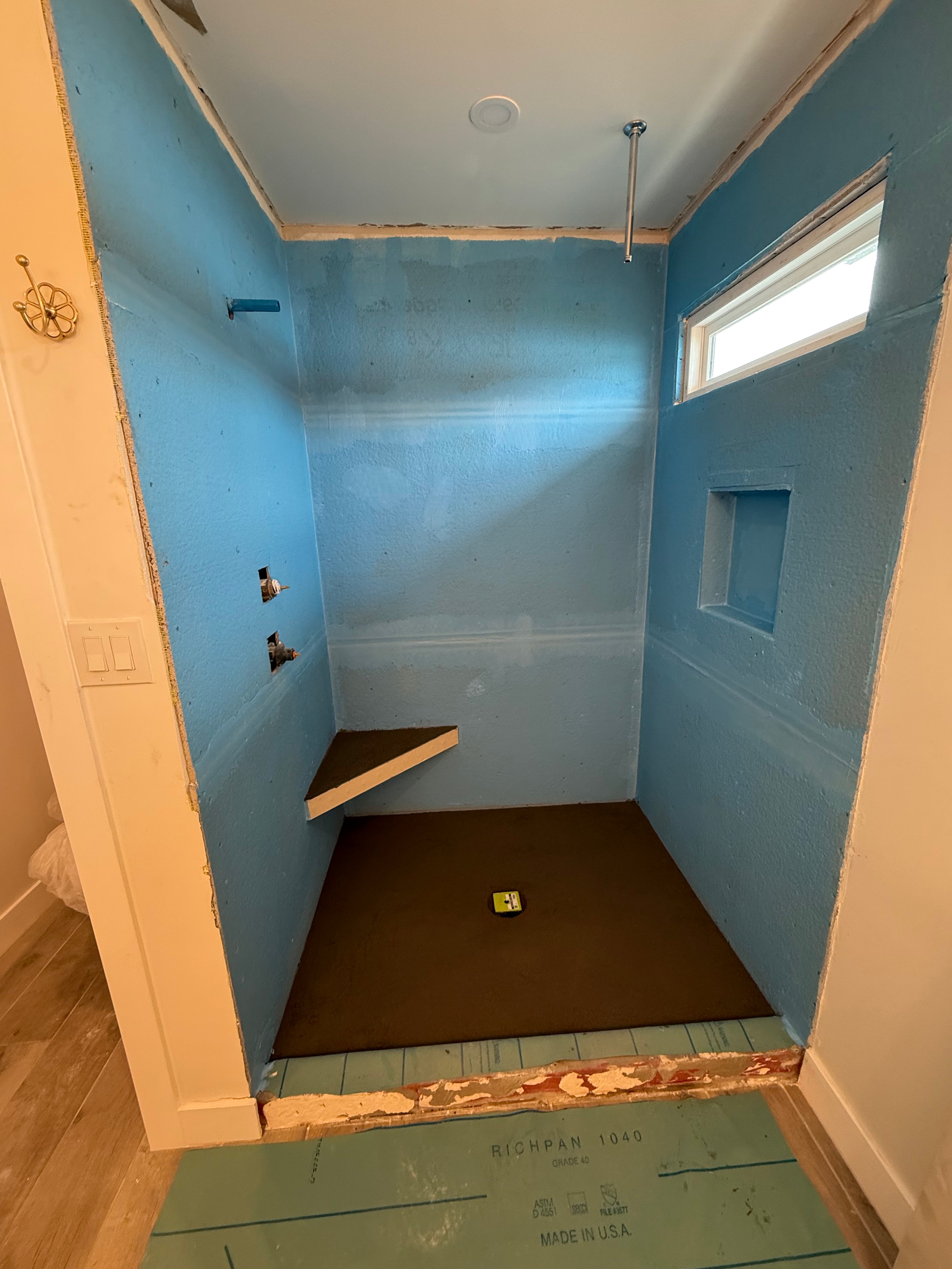 Waterproofed walk-in shower walls and floor ready for tile installation